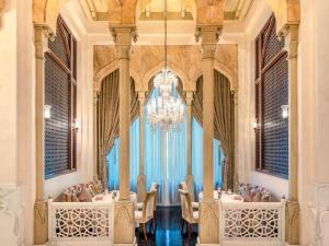 een eetkamer met een kroonluchter en tafels en stoelen bij Mövenpick Hotel Al Khobar in Al Khobar