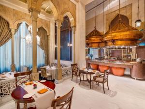 een restaurant met tafels en stoelen en een keuken bij Mövenpick Hotel Al Khobar in Al Khobar