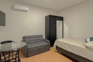 um quarto com uma cama, uma cadeira e uma mesa em Flats_Sabia em Uberlândia
