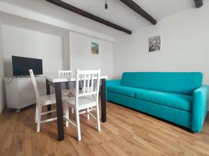 a living room with a blue couch and a table and chairs at Casa Petracca in Muggia