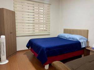 a bedroom with a blue bed and a window at Moderno departamento en Tula in Tula de Allende