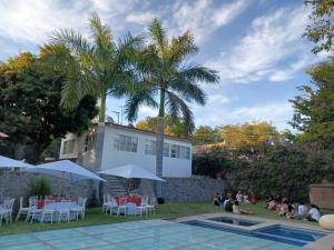 a group of people sitting around a pool with palm trees at Quinta las flores de Elizondo in Xochitepec