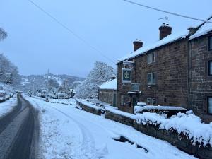 a street covered in snow next to a building at Jug and glass in Highpeak Junction