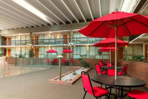 a cafeteria with tables and chairs with red umbrellas at Ramada by Wyndham Indiana in Indiana