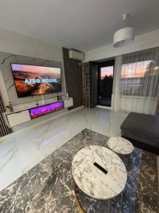 een woonkamer met 2 tafels en een flatscreen-tv bij Elegance Apartament in Mamaia