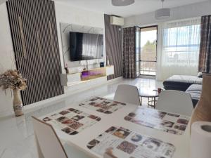 een woonkamer met een tafel met stoelen en een televisie bij Elegance Apartament in Mamaia