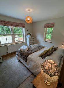 a bedroom with a bed and a table and windows at Luxury Woodland Stay in Cheltenham in Cheltenham