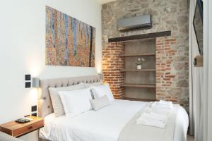 a bedroom with a white bed and a brick wall at MONOPATI HOUSE in Mouzaki