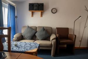 a living room with a couch and a clock on the wall at Ferienwohnung " Lee " in Neuharlingersiel