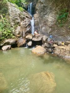zwei Leute sitzen auf Felsen neben einem Wasserfall in der Unterkunft UNDE Village Camp Morogoro in Morogoro + 1 Foto