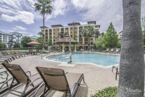 Un complejo con piscina y sillas y un edificio. en Pool view Condo near all Parks, en Orlando