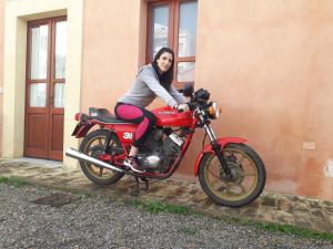 a woman is sitting on a red motorcycle at Oasi Ottocento in Quartu SantʼElena