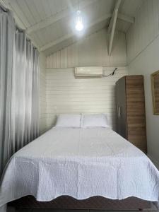 a bedroom with a large bed with a white comforter at Cabanas Sitio Berebello in Imaruí +11 photos