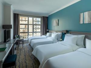 a row of white beds in a hotel room at Anwar Al Madinah Mövenpick in Al Madinah