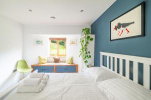 a bedroom with a white bed and a blue wall at Sedum House 8 in Gimingham