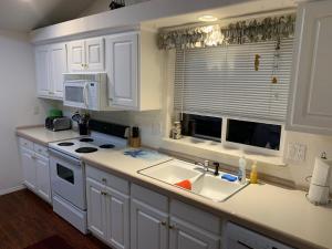 a kitchen with white cabinets and a sink and a microwave at 3-bedroom house Rockaway Beach in Rockaway Beach