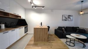 a living room with a black couch and a kitchen at Stylish Lumen Apartment Luxury Stay and Free Parking in Sarajevo