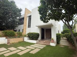 a white house with a grass yard in front of it at BK's Villa Golf - By the 7th Hole in Ahmedabad