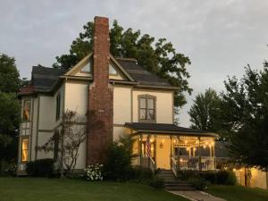a white house with a brick chimney and lights at Temple View Inn with Music Studio in Independence