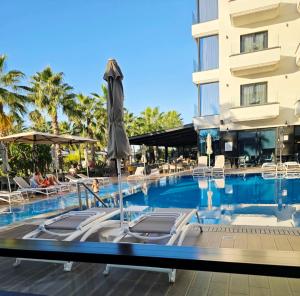 a pool at a hotel with chairs and an umbrella at 60 seconds walk to the Beach in Golem