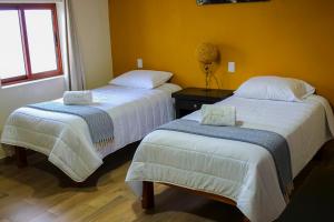 two beds in a room with yellow walls at Casa Romano in Tlatlauquitepec +8 photos