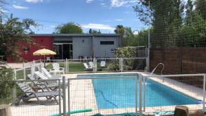 a swimming pool with chairs and a fence around it at Ideal Alojamiento in Lunlunta