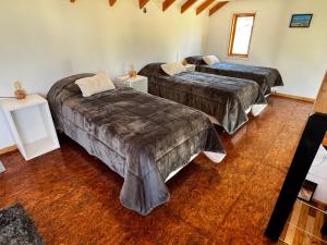 two beds in a room with wooden floors at Cabañas Los Manzanos in Cholila