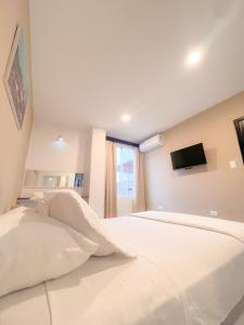a bedroom with a large white bed with a flat screen tv at Habitación con terraza in Puerto Ayora