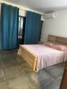 Un dormitorio con una cama grande con cortinas azules. en Oreo - Destination Guyane, en Saint-Laurent-du-Maroni