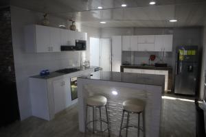 a kitchen with white cabinets and a island with bar stools at Penthouses La Fe in Cartagena de Indias