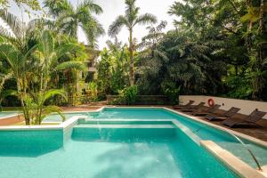 a swimming pool with chairs and palm trees at Uvita Paradise , Walk to the Ballena Beach in Uvita