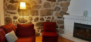 a living room with a stone fireplace and a red couch at Casa de Partida in Covilhã