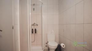 a white bathroom with a shower and a toilet at Apartamento acolhedor com AC no centro de Angra in Angra do Heroísmo +7 photos