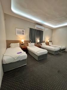 a hotel room with three beds in a room at التطوير الحضري فندق عقيق شارع ابراهيم الخليل in Al Masfalah