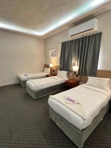 a hotel room with three beds and a window at التطوير الحضري فندق عقيق شارع ابراهيم الخليل in Al Masfalah