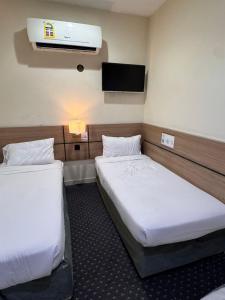 a hotel room with two beds and a tv at التطوير الحضري فندق عقيق شارع ابراهيم الخليل in Al Masfalah