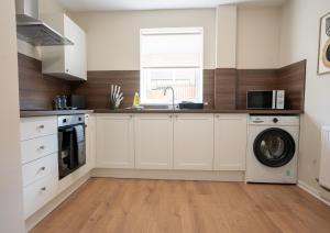 Una cocina con gabinetes blancos y lavadora y secadora. en Beechwood House, en Cadzow