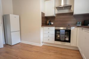 Una cocina con gabinetes blancos y un refrigerador. en Beechwood House, en Cadzow 24 fotos más
