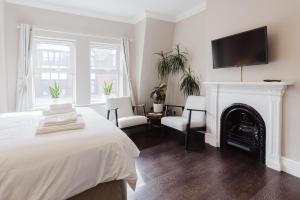 a white bedroom with a fireplace and a tv on the wall at Grace's Guesthouse Room 2 in Tring