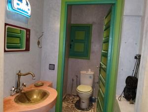 baño con lavabo de oro y aseo en Riad Yousra, en Marrakech