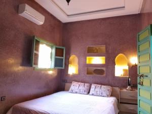 Un dormitorio con una cama y dos ventanas en Riad Yousra, en Marrakech