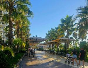 a group of people walking down a street with umbrellas at 60 seconds walk to the Beach in Golem