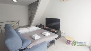 a room with a bed and a couch and a tv at Terraço e vista deslumbrante no centro de Angra in Angra do Heroísmo