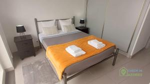 a bedroom with a bed with two towels on it at Terraço e vista deslumbrante no centro de Angra in Angra do Heroísmo