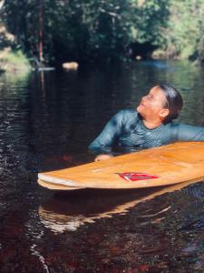 a man laying on a surfboard in the water at Sítio com suítes e áreas de Lazer in Palmeiras