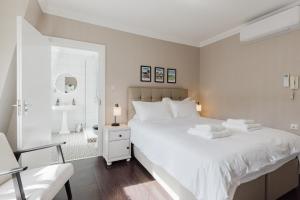 a white bedroom with a large bed and a chair at Grace's Guesthouse 68a in Tring