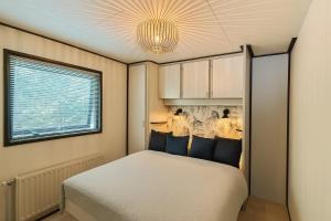 a small bedroom with a bed and a chandelier at Gezellig chalet met 2 slaapkamers aan bosrand in Erm