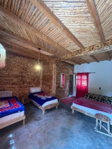 a room with three beds and a brick wall at Gite Cathedrale Imsfrane in Temga +17 photos