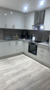 a kitchen with white cabinets and a wooden floor at Bright Studio Near Kew Gardens & Heathrow in Hounslow