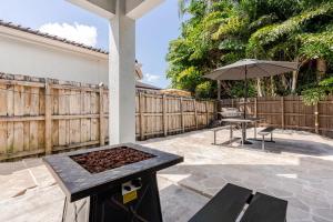 a patio with a table and an umbrella at FL1 House NEW Miami Oasis Game Room & Firepit in Tamiami